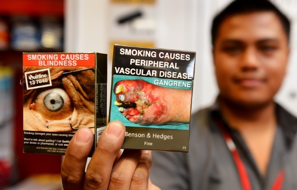 Nové odpudivé obaly cigaret v Austrálii. Vlevo: Cigarety mohou způsobit ztrátu zraku. Vpravo: Cigarety mohou způsobit ucpání cév, které pak vede k odumírání tkáně.